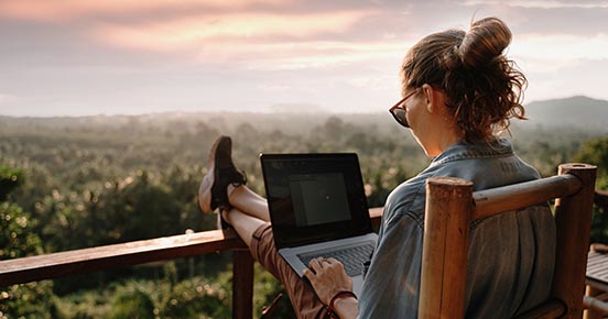 Woman with a laptop sitting on a balcony with a great view